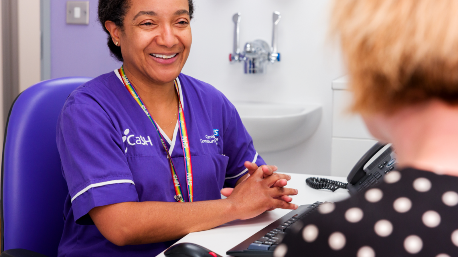 Smiling Icash Nurse Speaking To A Service User At A Desk 4X3