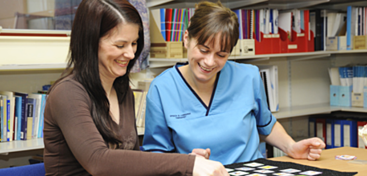 Speech And Language Therapist Helping Woman With Communication Cards