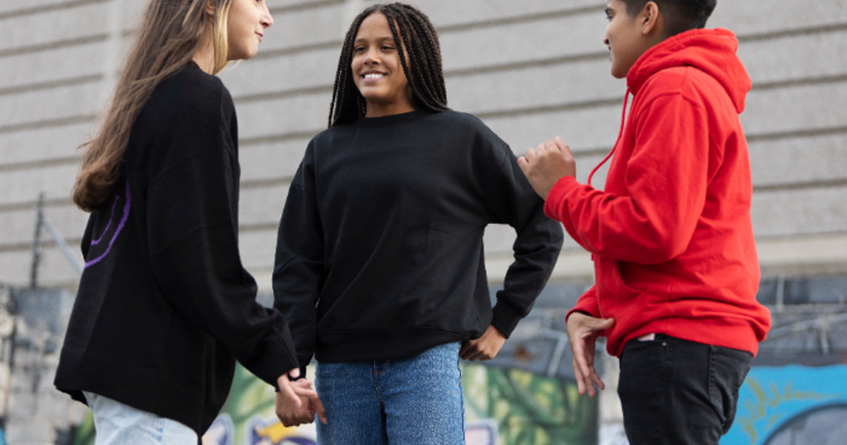 Three teenagers standing outside in front of a graffiti wall