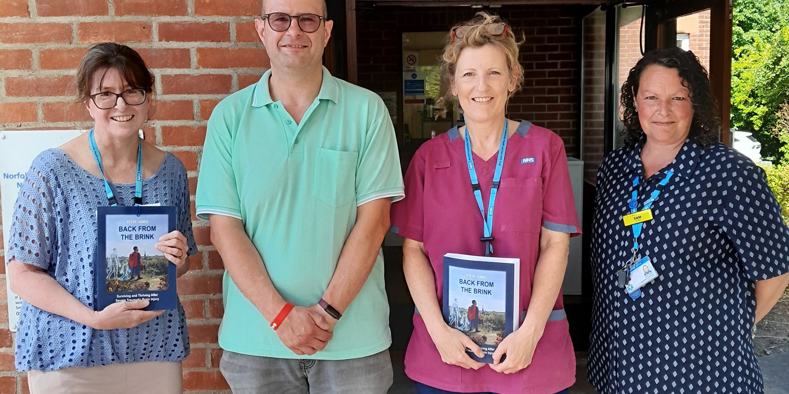 Dr Steve Jones presenting his book 'Back from The Brink: Surviving and Thriving After Severe Traumatic Brain Injury' to Judith, Rachel, Samantha and Daisy