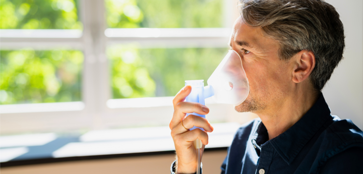 Man Using Inhaler Near Window