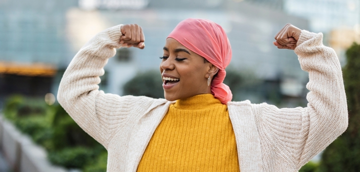 Woman in headscarf smiling and flexing her muscles