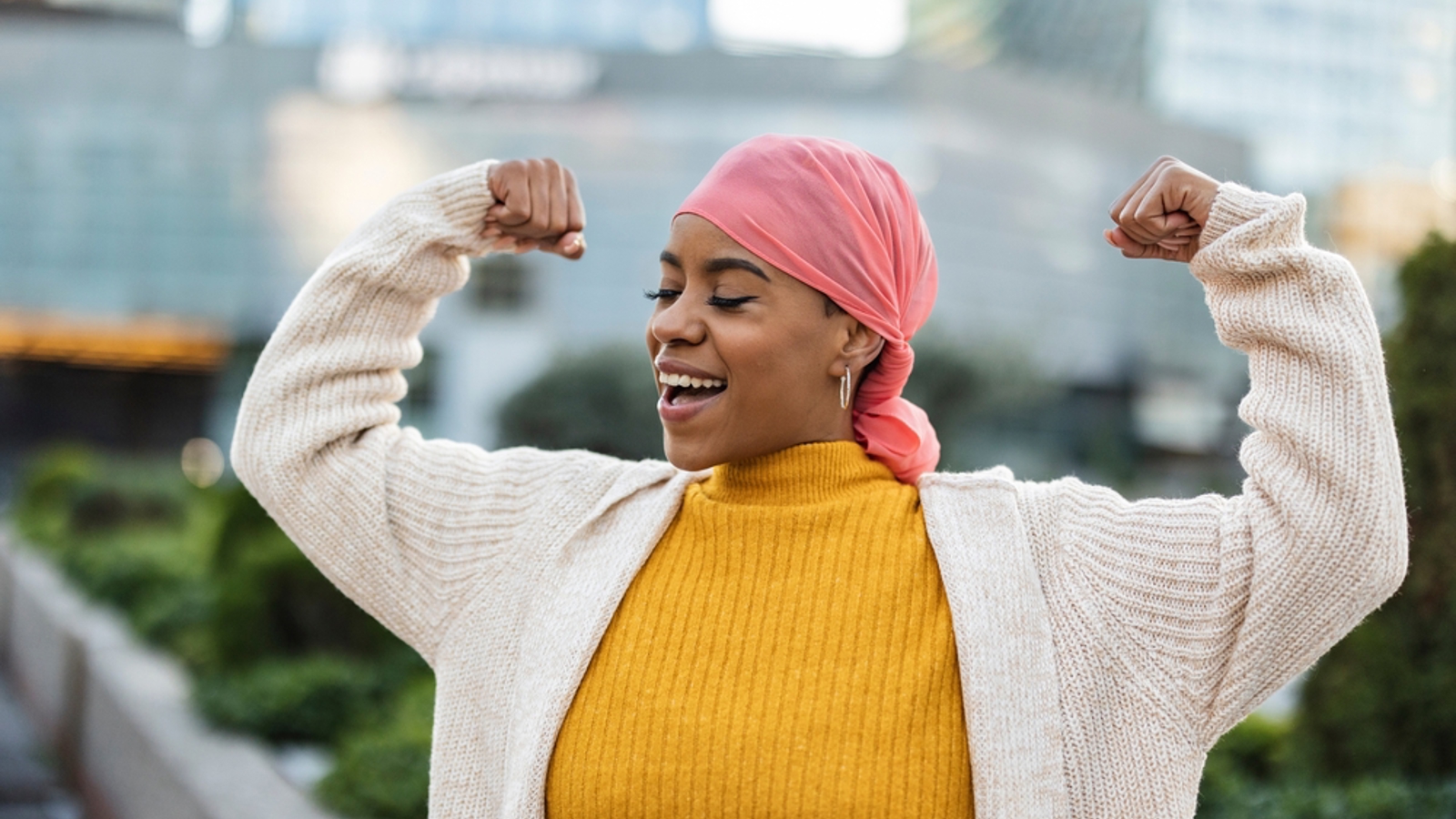 Woman in headscarf smiling and flexing her muscles