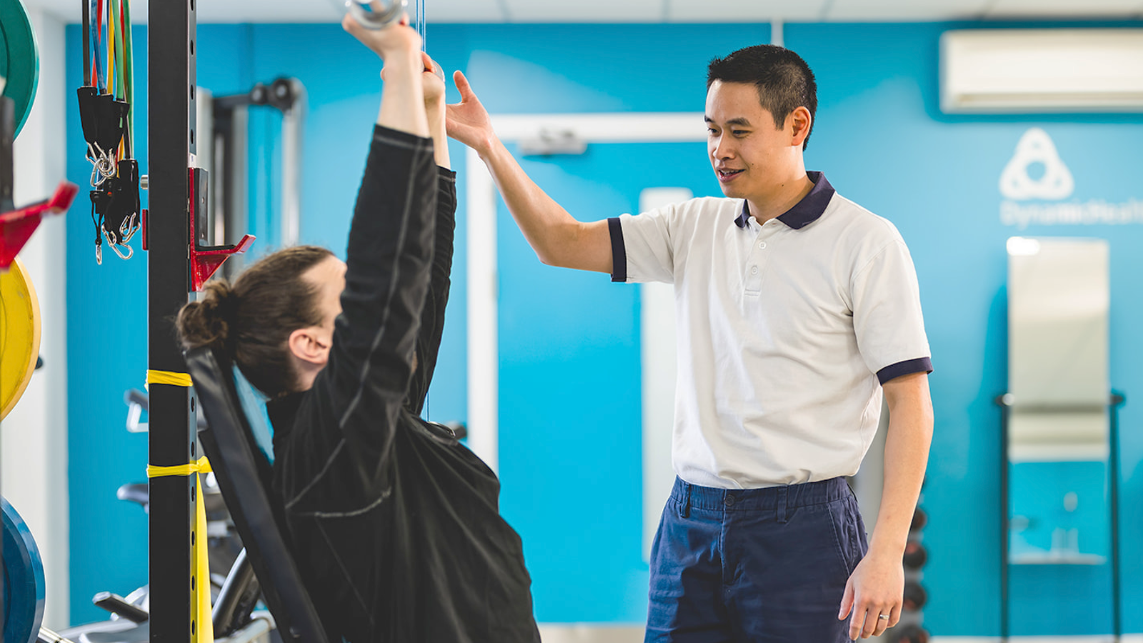 Physiotherapist helping patient with seated bench press