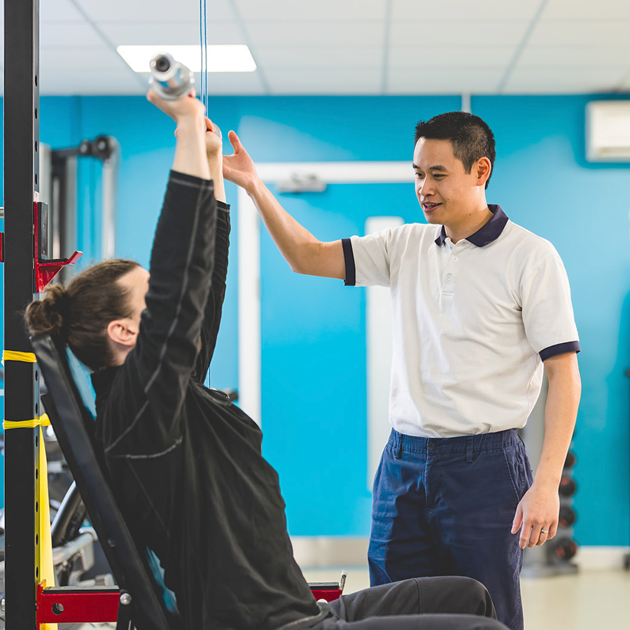Physiotherapist helping patient with seated bench press