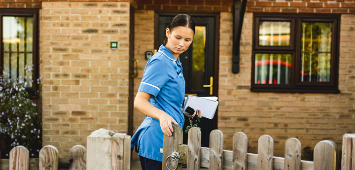 Community nurse closing a gate behind them as they approach a home.