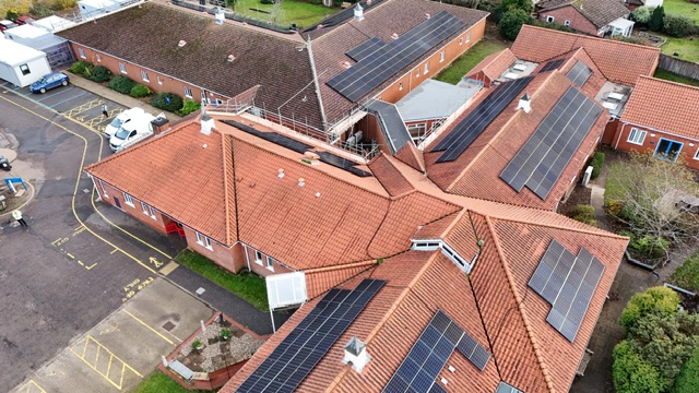 An aerial shot of North Walsham hospital. The shot shows a cross shaped building and an L shaped building both of which have new solar panels installed on the roof