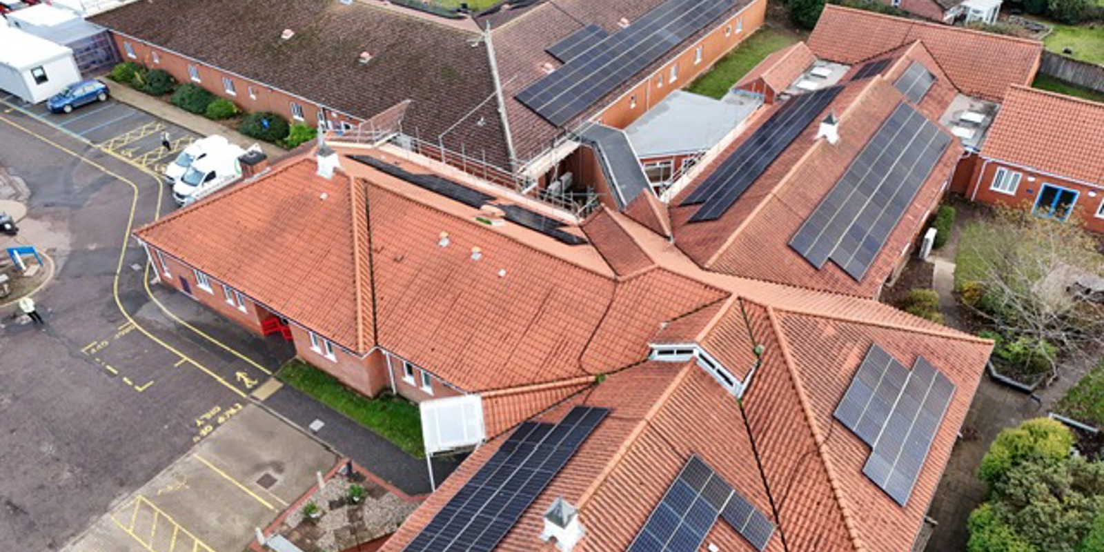 An aerial shot of North Walsham hospital. The shot shows a cross shaped building and an L shaped building both of which have new solar panels installed on the roof