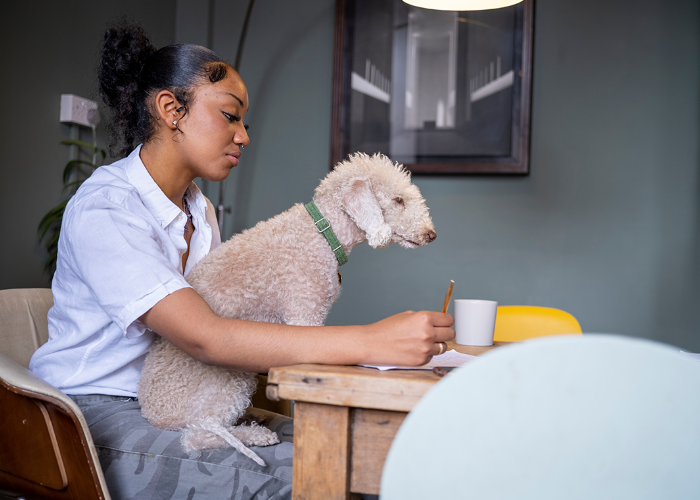 Teenage girl sitting at kitchen table with a dog on her lap