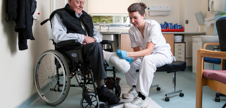 Elderly Man In Wheelchair Being Fitted With A Prosthetic Leg By Clinician
