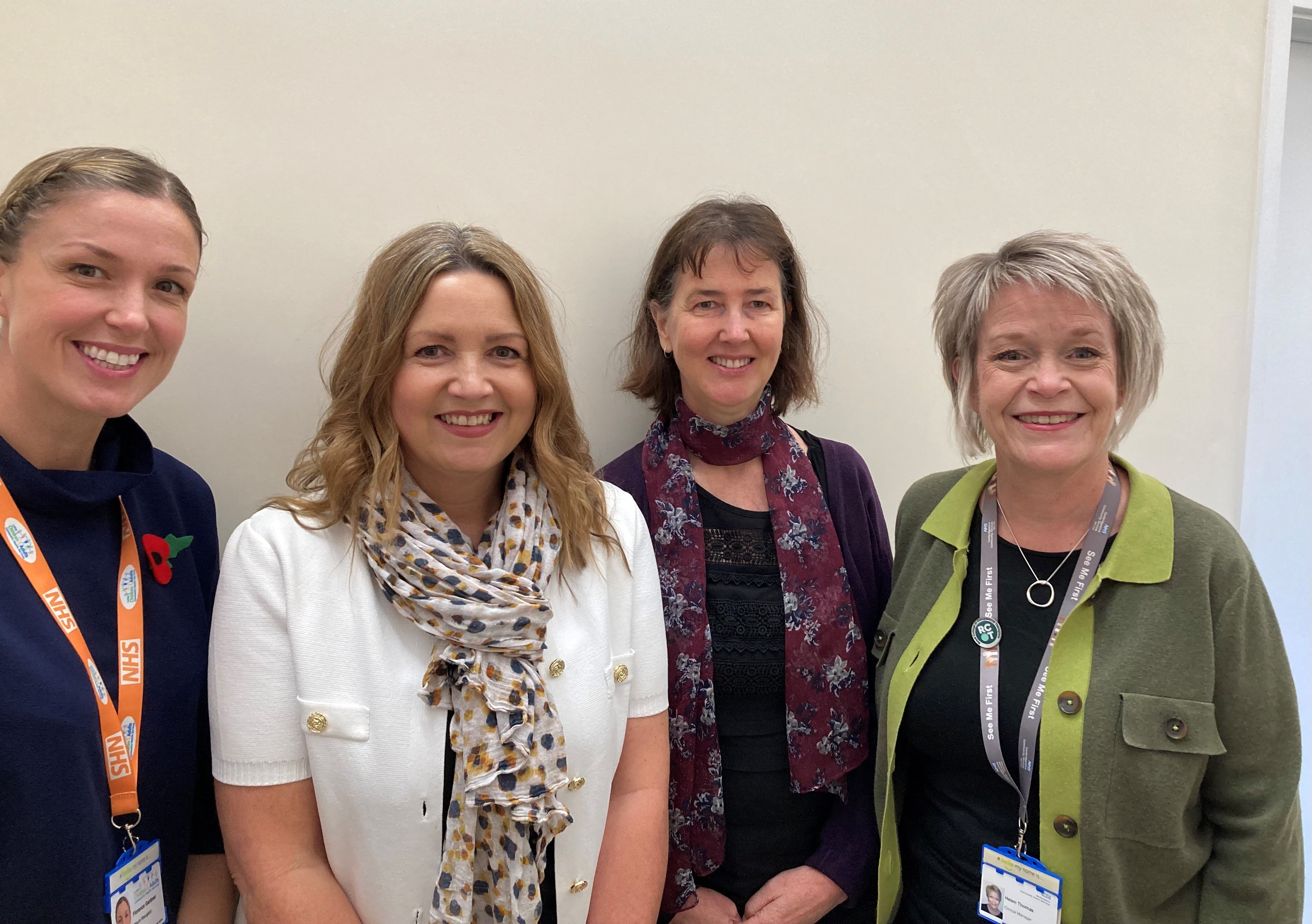 A photo of four women all wearing NHS lanyards, they are smiling
