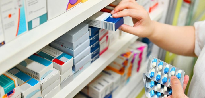 Pharmacist pulling out medications from pharmacy shelves.