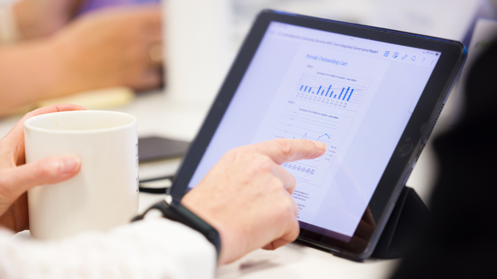 Hand pointing at a tablet screen