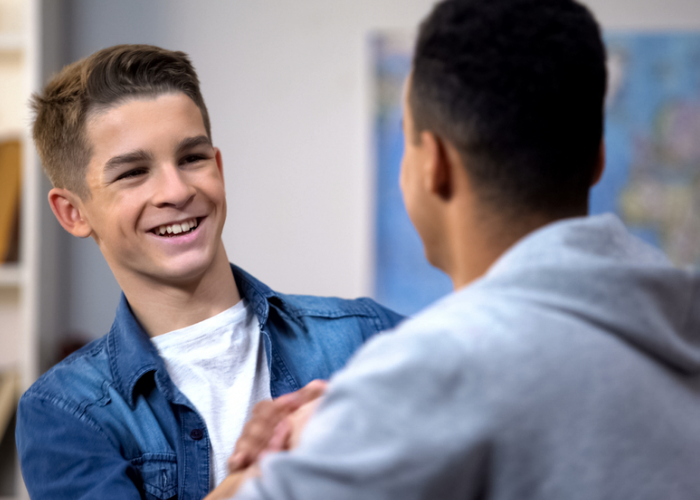 Two teenage boys shaking hands and smiling