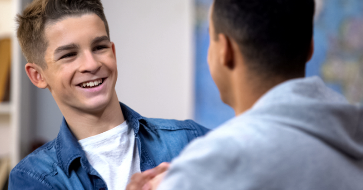 Two teenage boys shaking hands and smiling