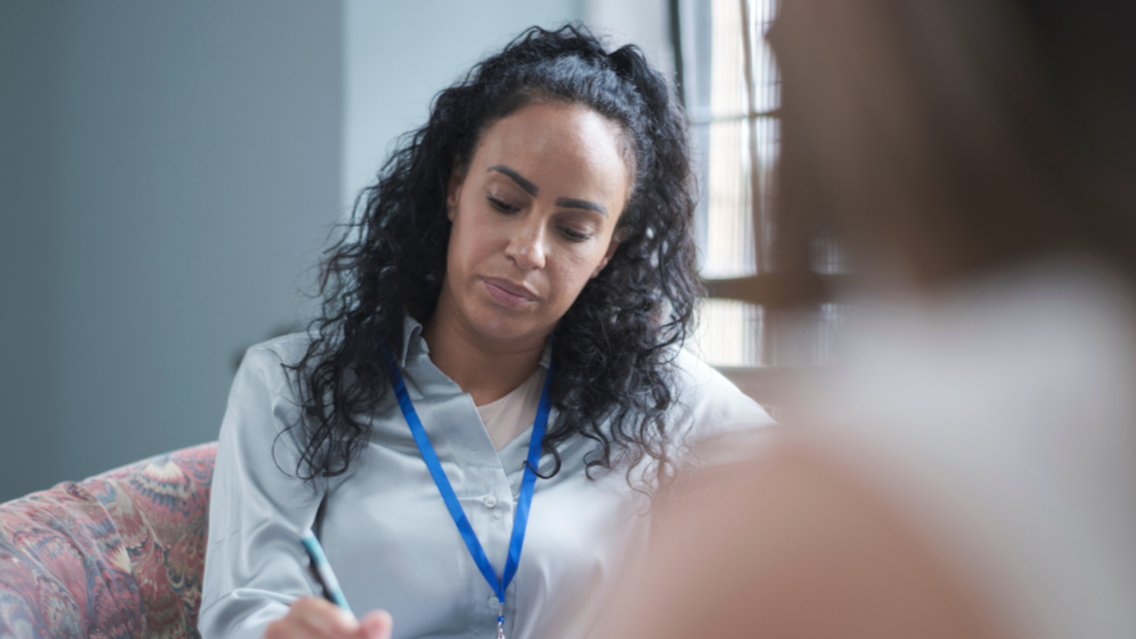 Woman in NHS lanyard writing notes