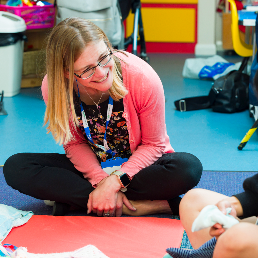 Clinician Smiling At Parent And Baby Sitting On The Floor Amended